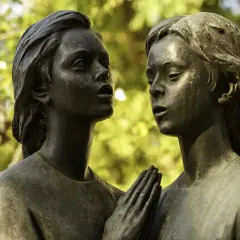 Deux visages d'anges en bronze se font face. Leurs mains jointes aident à comment reconnaître du bronze, patiné par le temps.