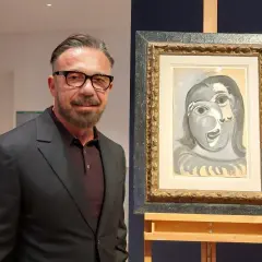 Un homme en costume pose à côté d'un tableau de Picasso, une œuvre qui pourrait bien battre des records de prix.