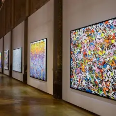 Une exposition d'art vibrante, avec des toiles colorées de **JonOne** côte à côte, capturant l'énergie du graffiti.