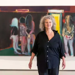 La peintre Marlene Dumas pose devant ses œuvres d'art, des figures floues dans des teintes vives.