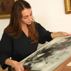 Une femme examine un tableau abstrait, prête à le faire estimer gratuitement.