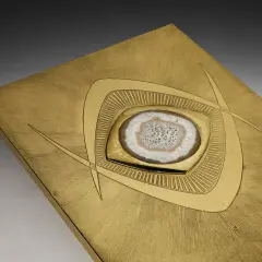Plaque en laiton brossé avec une agate polie incrustée, ornée de motifs géométriques stylisés.