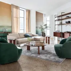 Salon moderne avec canapé beige, fauteuils verts et étagères en bois, ambiance mid century.