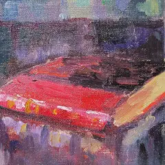 Un livre rouge vif, peut-être une œuvre de Robert Antoine Pinchon, repose sur une table, baigné de lumière.