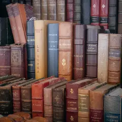 Une pile de livres anciens aux reliures variées. Obtenez une estimation livres anciens gratuit pour vos trésors littéraires.