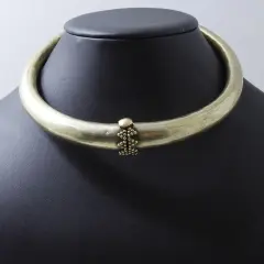 Collier rigide en laiton patiné, orné d'une grappe de perles. Un bijou d'exception, digne d'un prix Goudji.