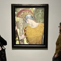 Deux femmes contemplent une peinture d'Hermine David représentant une figure casquée en armure dorée, tenant une lance.