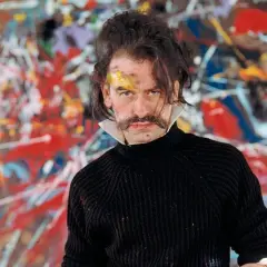 Georges Mathieu, lauréat du prix, pose devant une toile abstraite vibrante, son visage marqué par la peinture.