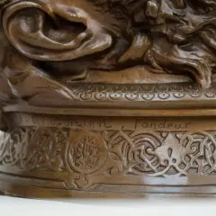 Détail d'une sculpture en bronze creux ou plein, ornée de motifs complexes et d'une inscription gravée.
