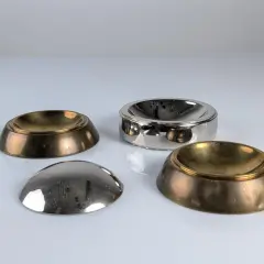 Quatre coupelles en laiton et argent, inspirées par le design de Tommaso Barbi, reflètent la lumière sur leur surface polie.