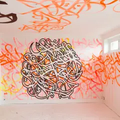 Un mur et un plafond recouverts de calligraphie arabe vibrante, comme si el seed avait semé des mots dans cet espace.