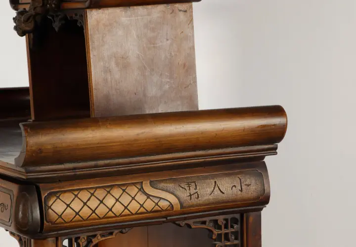 Détail d'un meuble en bois sculpté, orné de motifs géométriques et de caractères chinois, rappelant l'art de Gabriel Viardot.