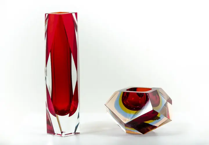 Deux vases en verre, un haut et rouge, l'autre facetté aux couleurs vives, signés Flavio Poli.