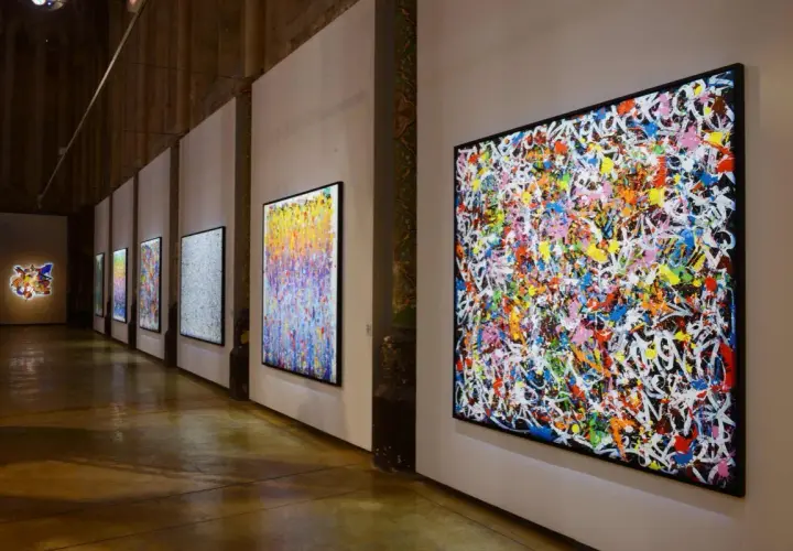 Une exposition d'art vibrante, avec des toiles colorées de **JonOne** côte à côte, capturant l'énergie du graffiti.