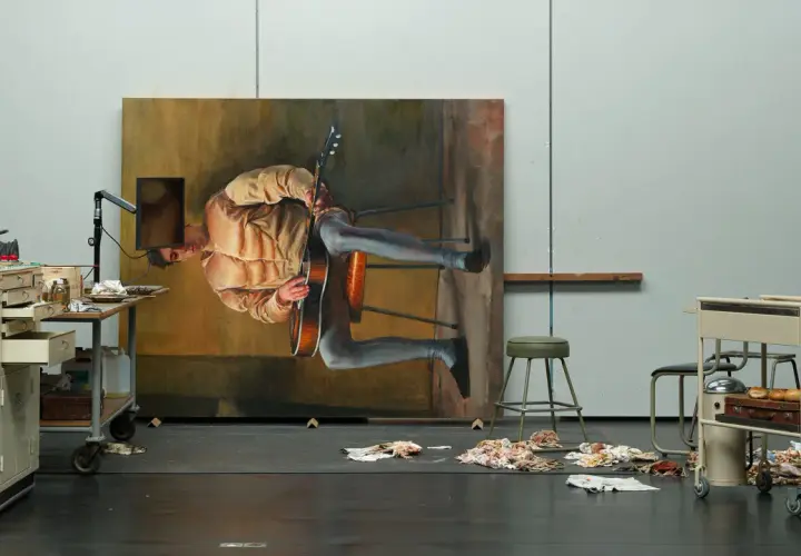 Dans l'atelier de Michael Borremans, un tableau monumental représente un homme jouant de la guitare, suspendu dans un espace onirique.