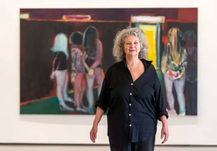 La peintre Marlene Dumas pose devant ses œuvres d'art, des figures floues dans des teintes vives.