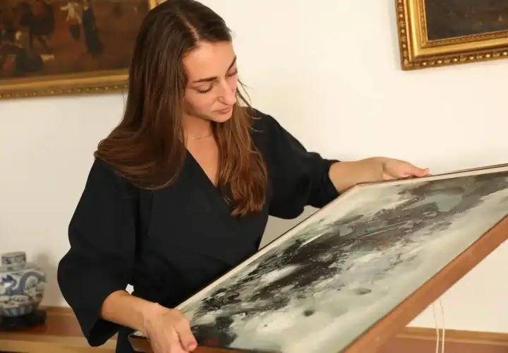 Une femme examine un tableau abstrait, prête à le faire estimer gratuitement.