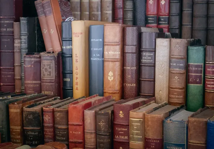 Une pile de livres anciens aux reliures variées. Obtenez une estimation livres anciens gratuit pour vos trésors littéraires.