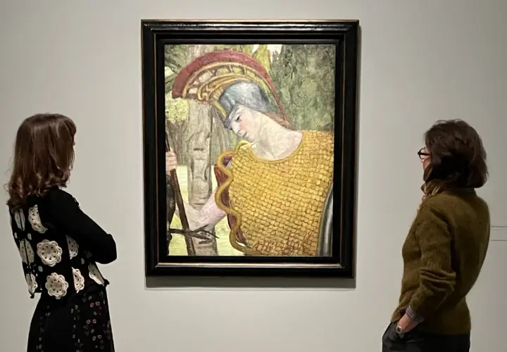 Deux femmes contemplent une peinture d'Hermine David représentant une figure casquée en armure dorée, tenant une lance.
