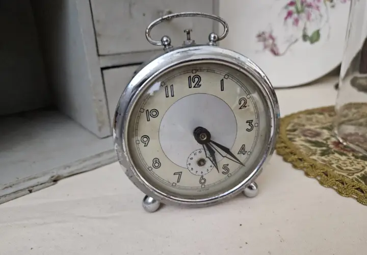 Un réveil ancien, objet de collection, prêt pour une estimation. Son cadran patiné et ses aiguilles racontent une histoire.