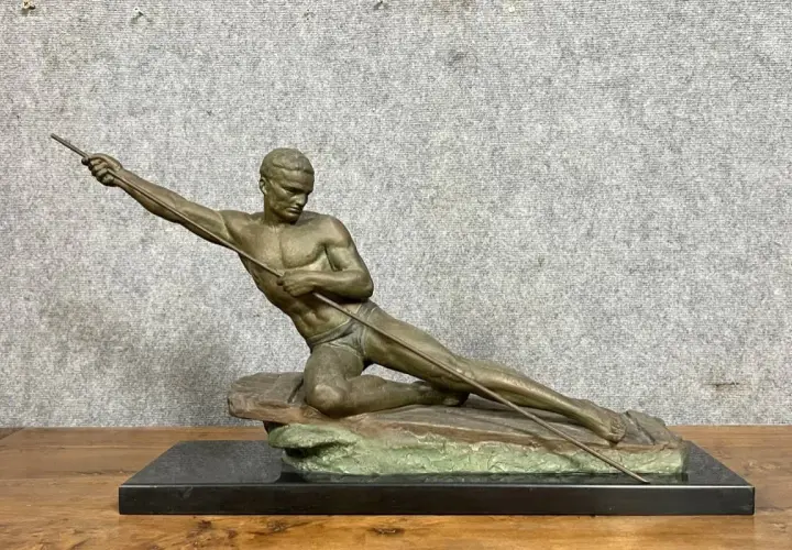 Sculpture en bronze ou régule d'un athlète lançant un javelot, posé sur un rocher.