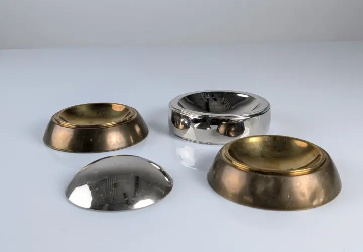 Quatre coupelles en laiton et argent, inspirées par le design de Tommaso Barbi, reflètent la lumière sur leur surface polie.