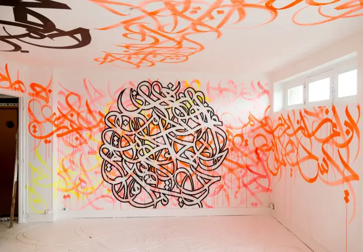 Un mur et un plafond recouverts de calligraphie arabe vibrante, comme si el seed avait semé des mots dans cet espace.