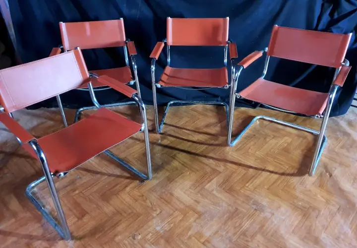 Quatre chaises modernes en cuir orange, style Matteo Grassi, sur un parquet en bois.