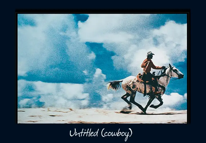 Un cowboy au chapeau monte un cheval blanc au galop sous un ciel bleu et nuageux, une œuvre emblématique de Richard Prince.