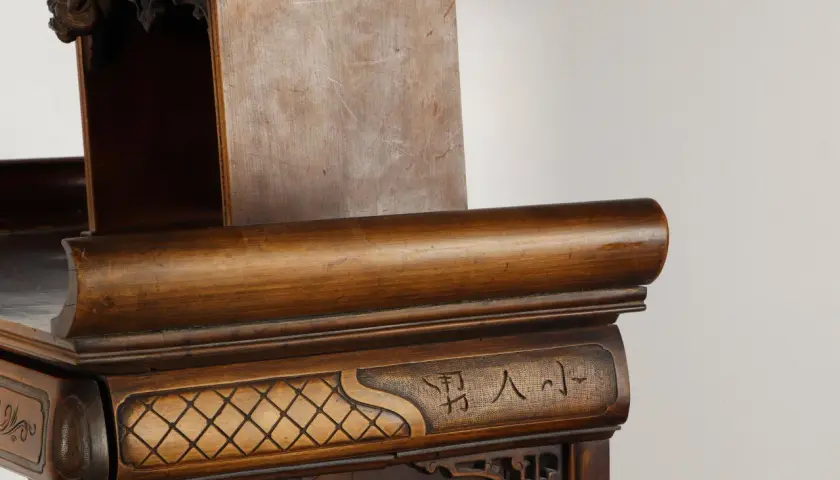 Détail d'un meuble en bois sculpté, orné de motifs géométriques et de caractères chinois, rappelant l'art de Gabriel Viardot.