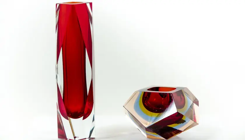 Deux vases en verre, un haut et rouge, l'autre facetté aux couleurs vives, signés Flavio Poli.