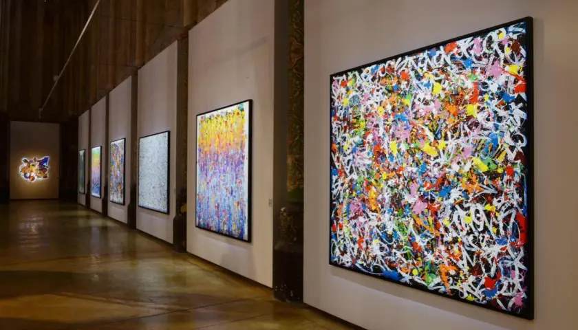 Une exposition d'art vibrante, avec des toiles colorées de **JonOne** côte à côte, capturant l'énergie du graffiti.