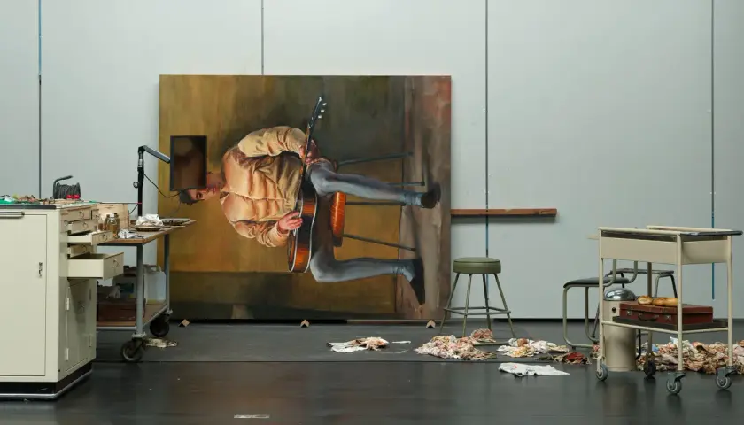 Dans l'atelier de Michael Borremans, un tableau monumental représente un homme jouant de la guitare, suspendu dans un espace onirique.
