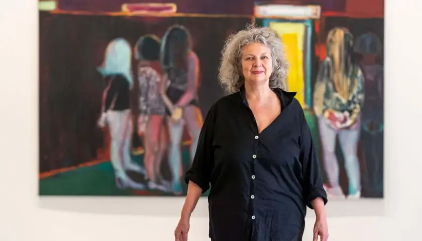 La peintre Marlene Dumas pose devant ses œuvres d'art, des figures floues dans des teintes vives.