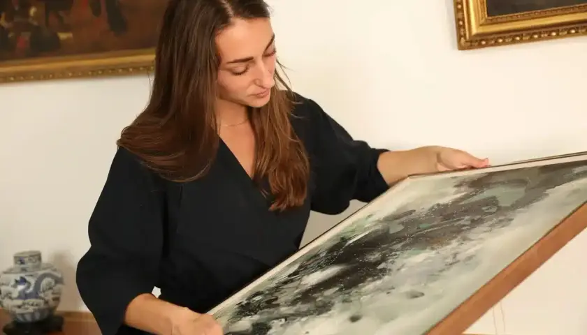 Une femme examine un tableau abstrait, prête à le faire estimer gratuitement.