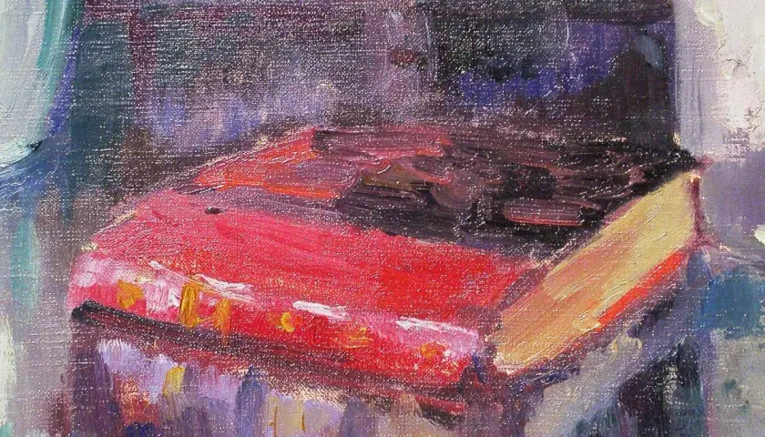 Un livre rouge vif, peut-être une œuvre de Robert Antoine Pinchon, repose sur une table, baigné de lumière.