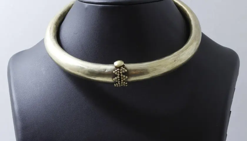Collier rigide en laiton patiné, orné d'une grappe de perles. Un bijou d'exception, digne d'un prix Goudji.
