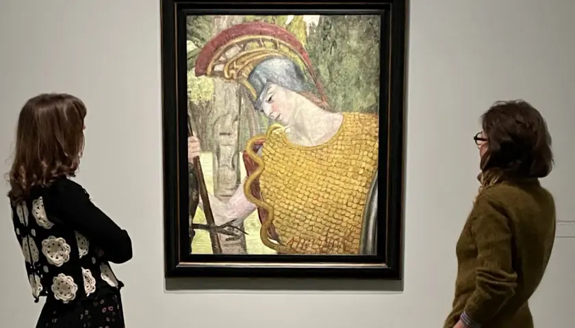 Deux femmes contemplent une peinture d'Hermine David représentant une figure casquée en armure dorée, tenant une lance.
