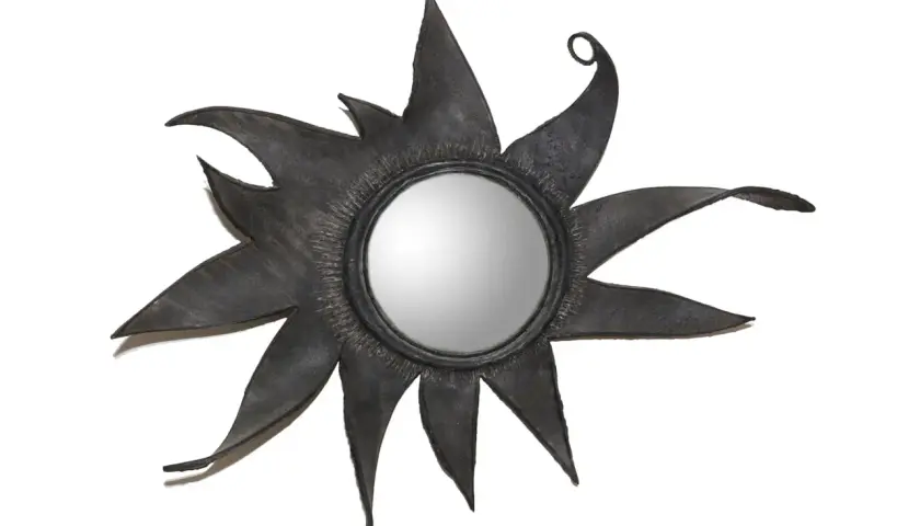 Miroir soleil en métal noir, aux rayons stylisés et pointus, rappelant l'éclat d'une étoile. Un design audacieux, digne d'une ligne Vautrin.