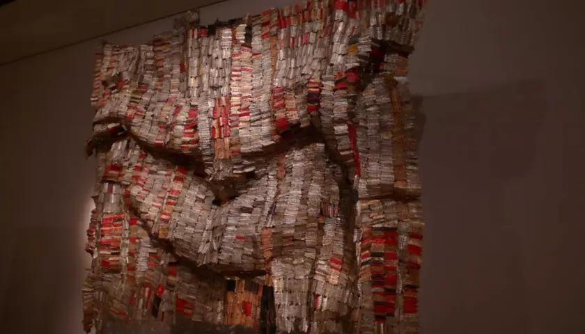 Œuvre monumentale d'El Anatsui, un rideau de bouchons de bouteilles en aluminium et cuivre, aux reflets changeants, évoquant des tissus précieux.