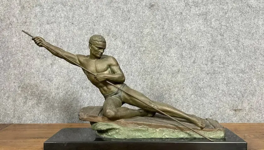 Sculpture en bronze ou régule d'un athlète lançant un javelot, posé sur un rocher.