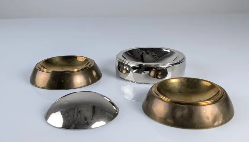 Quatre coupelles en laiton et argent, inspirées par le design de Tommaso Barbi, reflètent la lumière sur leur surface polie.