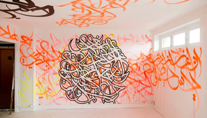 Un mur et un plafond recouverts de calligraphie arabe vibrante, comme si el seed avait semé des mots dans cet espace.