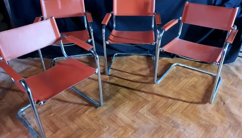 Quatre chaises modernes en cuir orange, style Matteo Grassi, sur un parquet en bois.