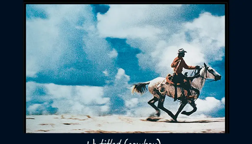 Un cowboy au chapeau monte un cheval blanc au galop sous un ciel bleu et nuageux, une œuvre emblématique de Richard Prince.