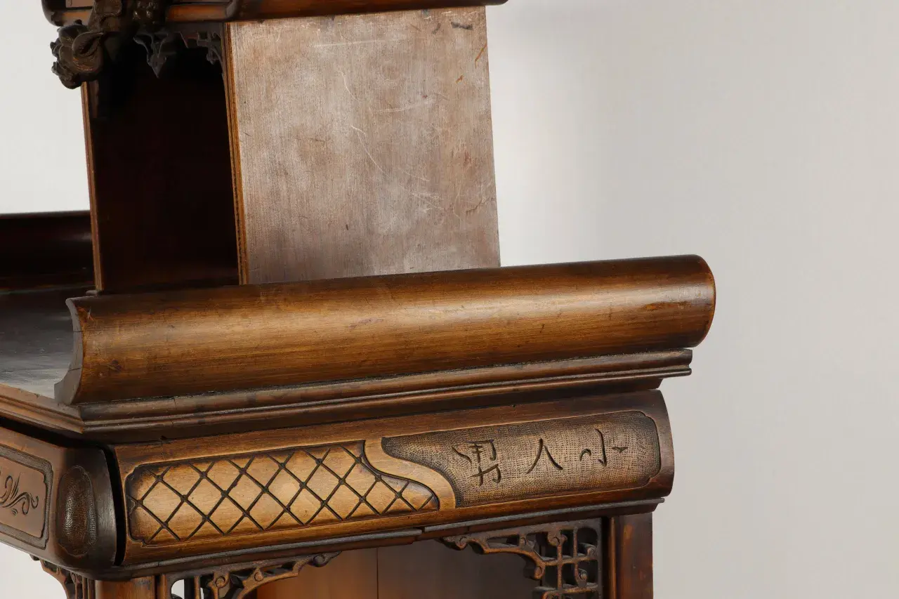 Détail d'un meuble en bois sculpté, orné de motifs géométriques et de caractères chinois, rappelant l'art de Gabriel Viardot.