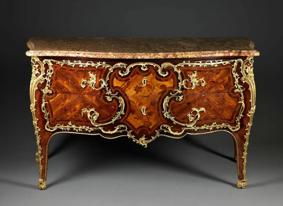Commode Louis XV en marqueterie de bois précieux, ornée de bronzes dorés. Une estampille sur ces meubles anciens témoigne de son artisanat d'art.