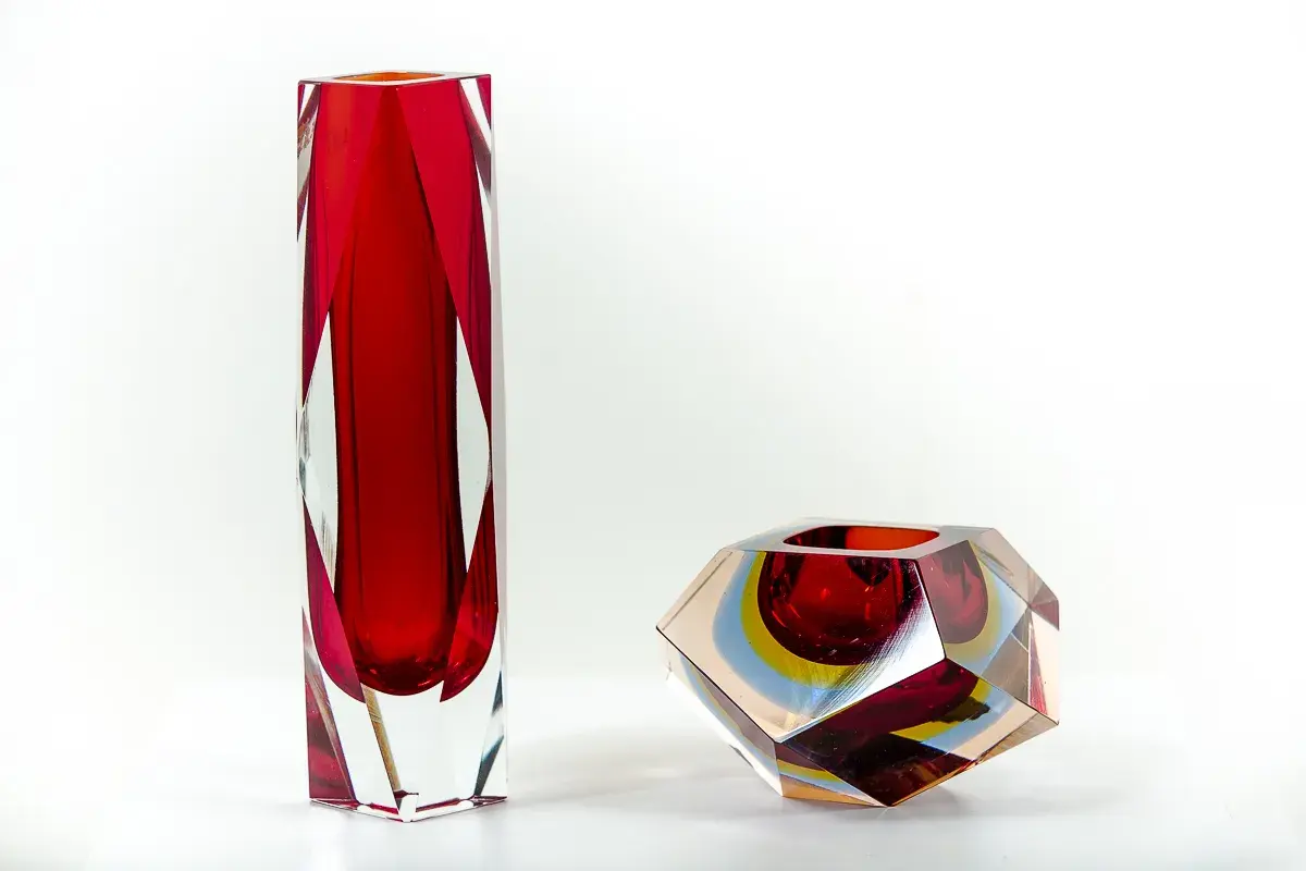 Deux vases en verre, un haut et rouge, l'autre facetté aux couleurs vives, signés Flavio Poli.