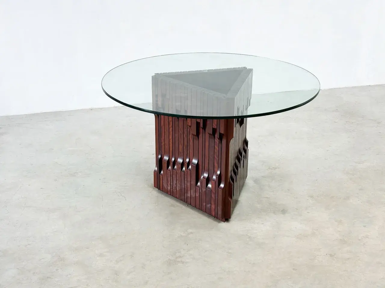 Table basse design en bois sculpté et verre, style Luciano Frigerio, avec un pied triangulaire unique.