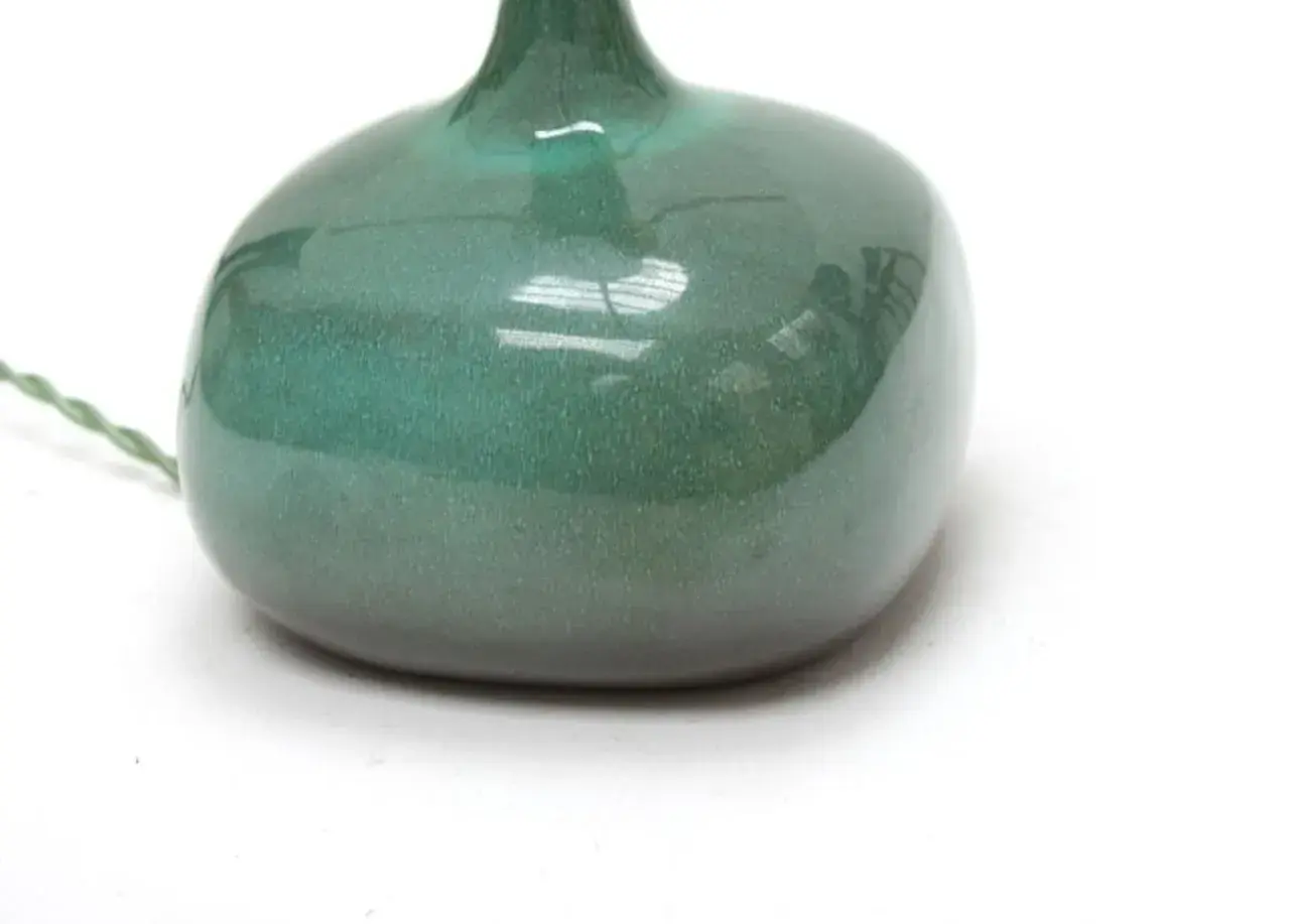 Base d'une lampe en céramique verte, œuvre de Jacques et Dani Ruelland, avec un fil électrique torsadé.